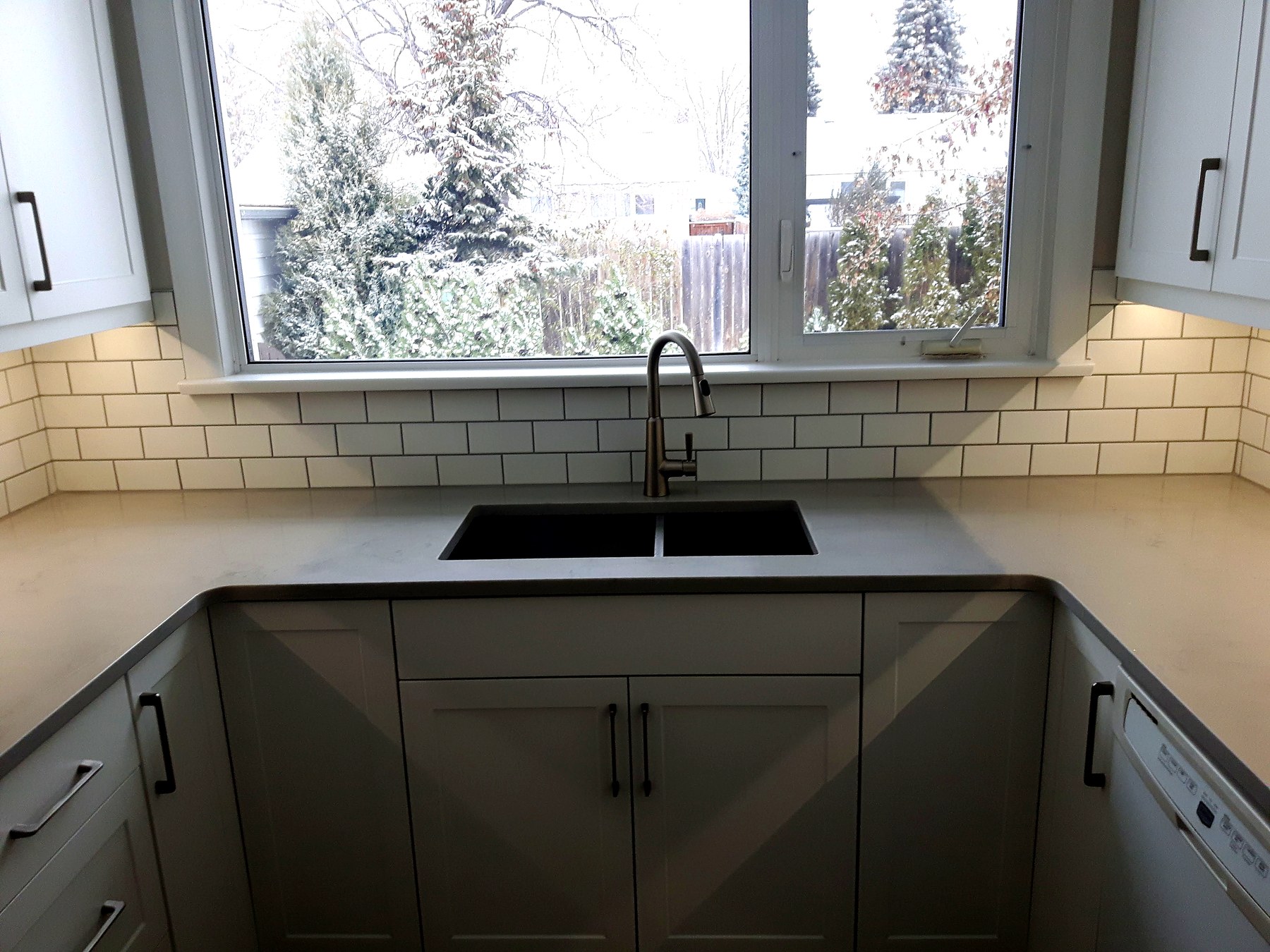 Winnipeg homeowner reviewing renovation plans at a bright kitchen sink window